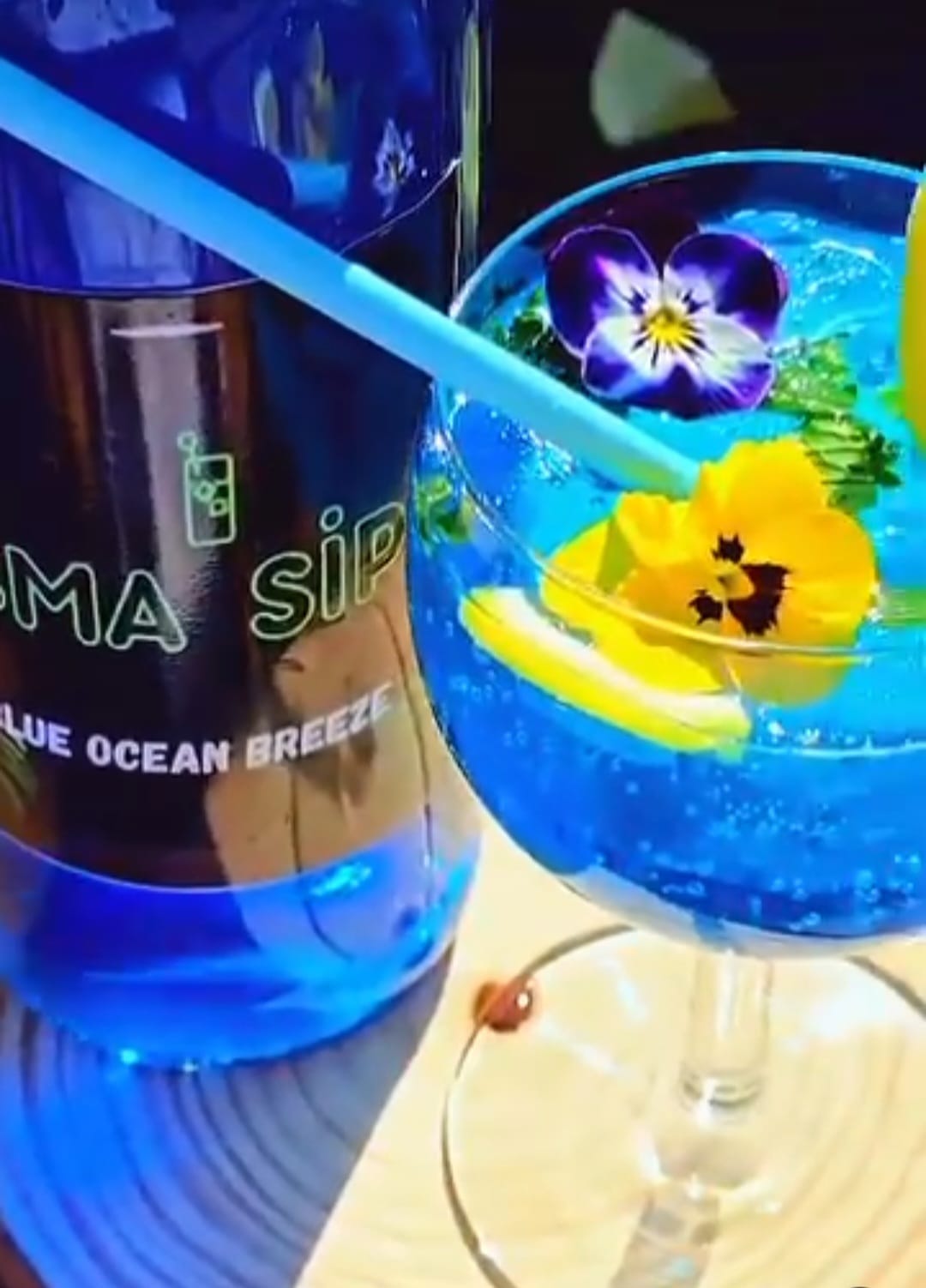Blue Ocean Breeze cocktail garnished with edible flowers and lemon